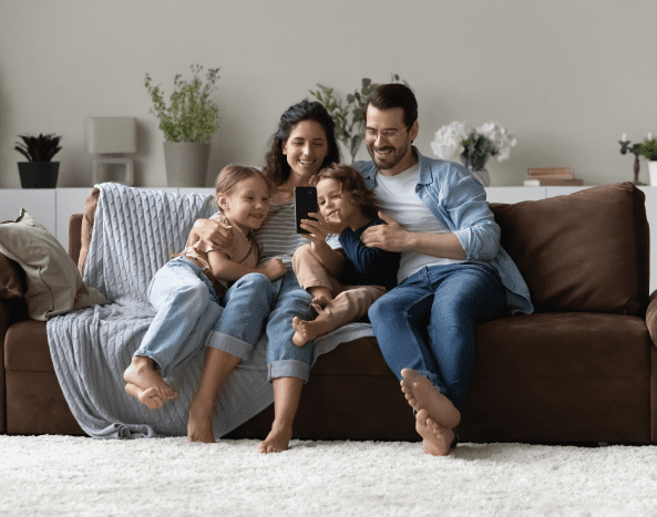 Happy family of four sitting closely on a cozy couch.